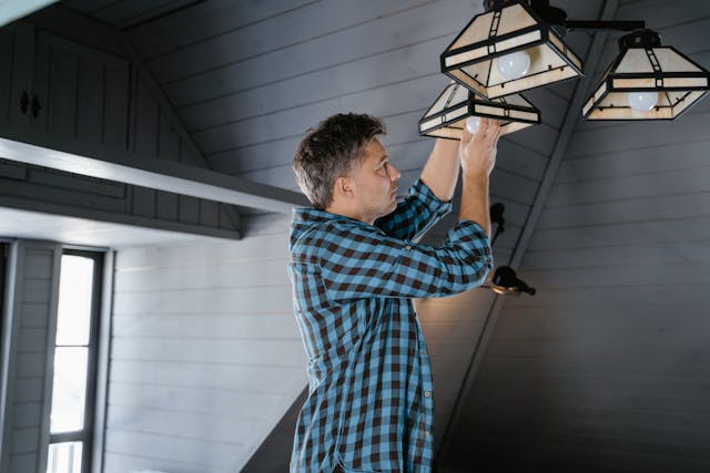 Person installing a light bulb on a hanging light fixture